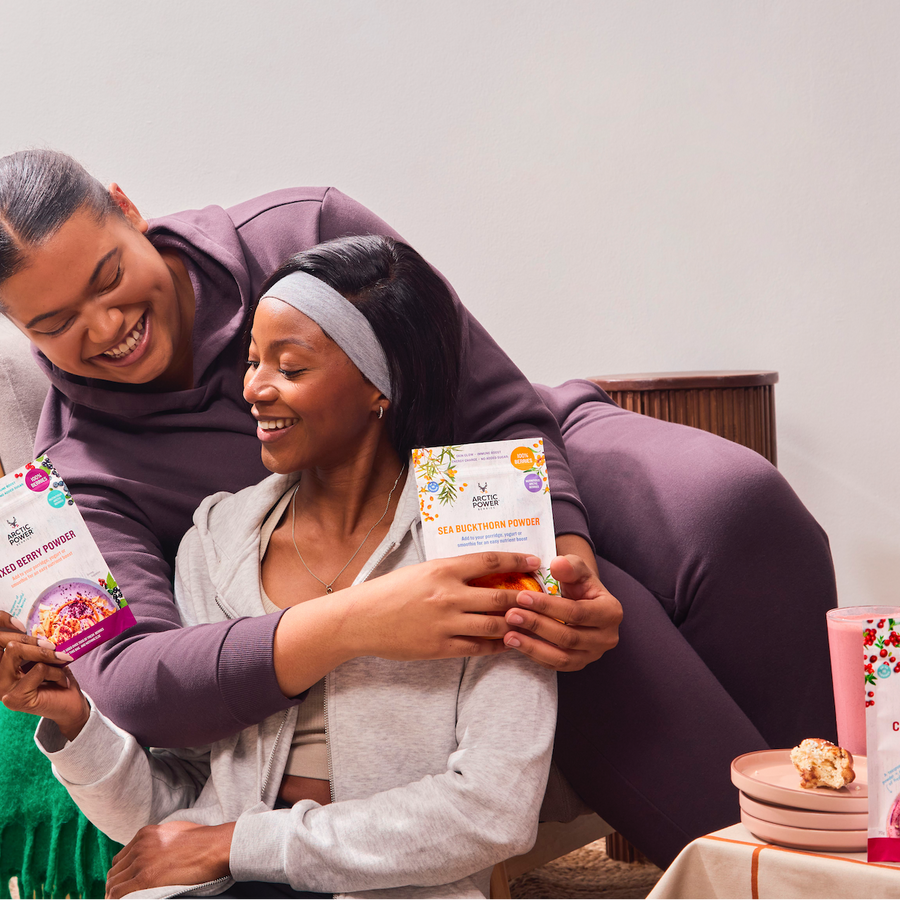 Two friends hugging and holding berry powder packaging